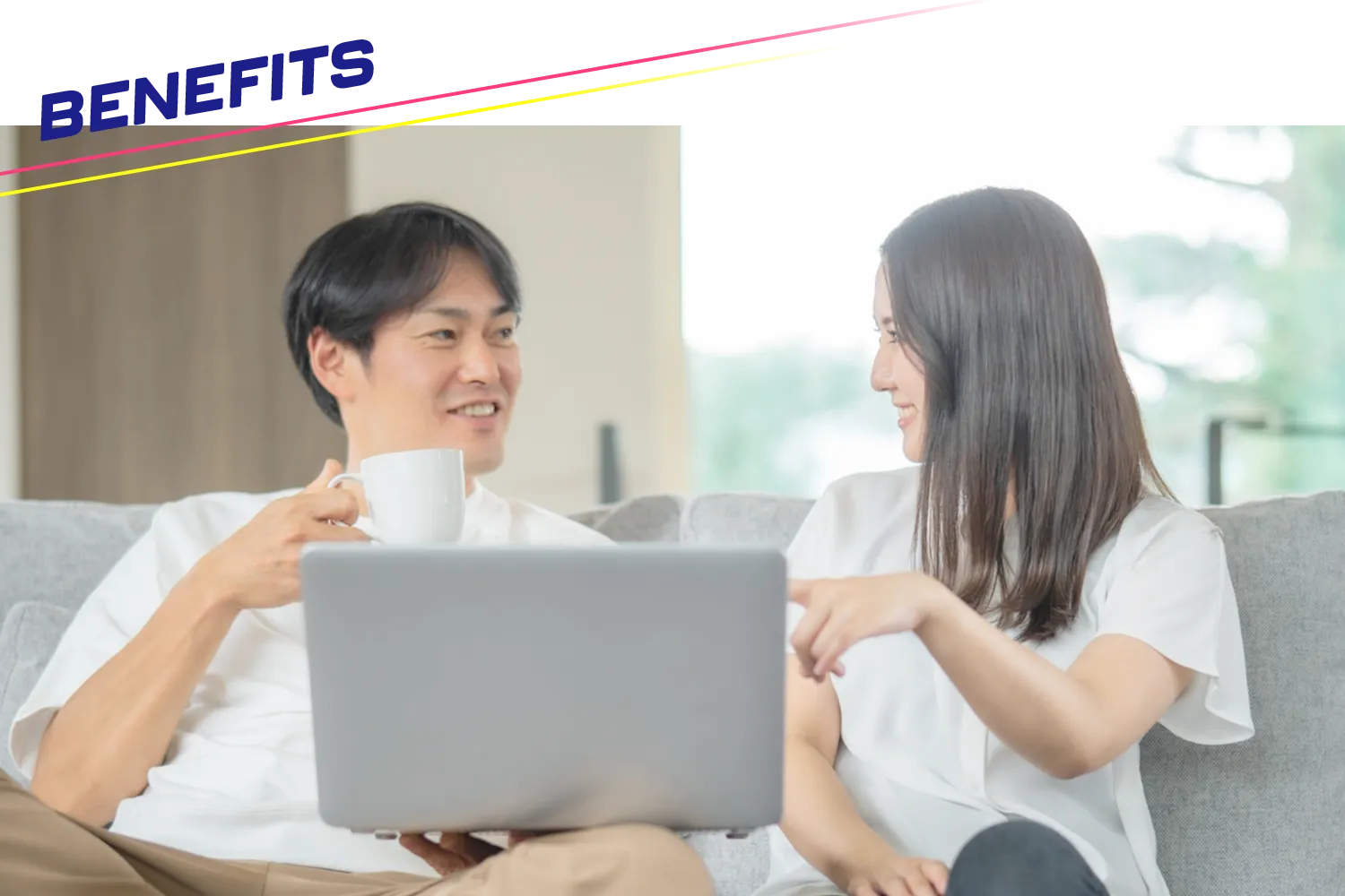 ソファの上でパソコンを見ながら談笑する男女